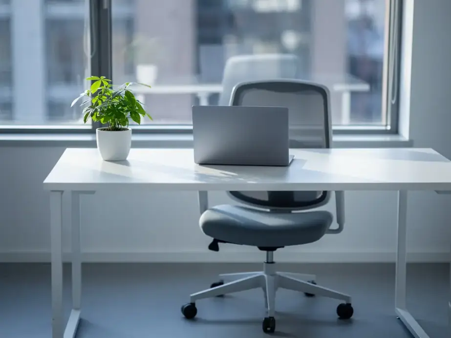 A wiped white desk by a window with the chair pushed in, ready for the workday